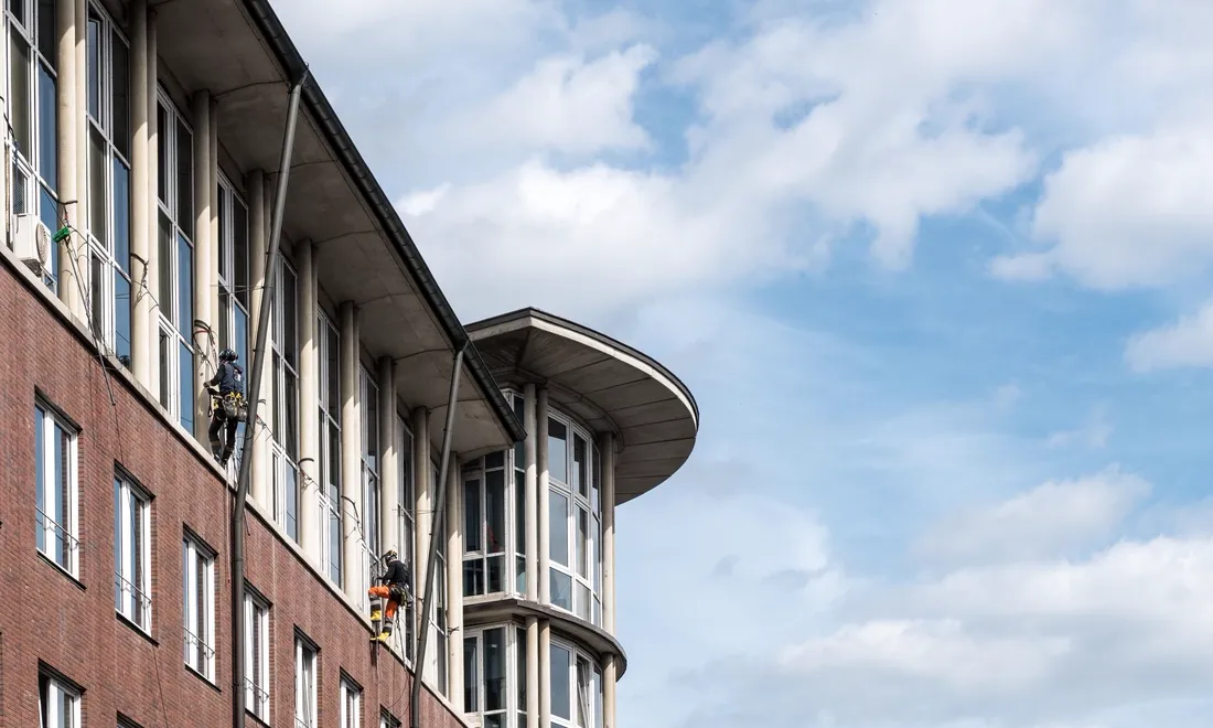 Zwei Fensterreiniger arbeiten an der Glasfassade eines modernen Gebäudes in Hamburg
