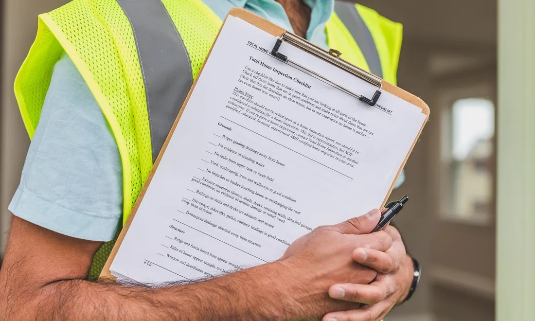 Person hält ein Klemmbrett mit einer Objektcheckliste und einem Stift